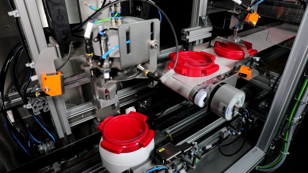 Installation pour le remplissage de poudre métallique dans des bouteilles, des bidons ou d'autres récipients. L'image montre la station de fermeture de la bouteille remplie avec un bouchon à vis.