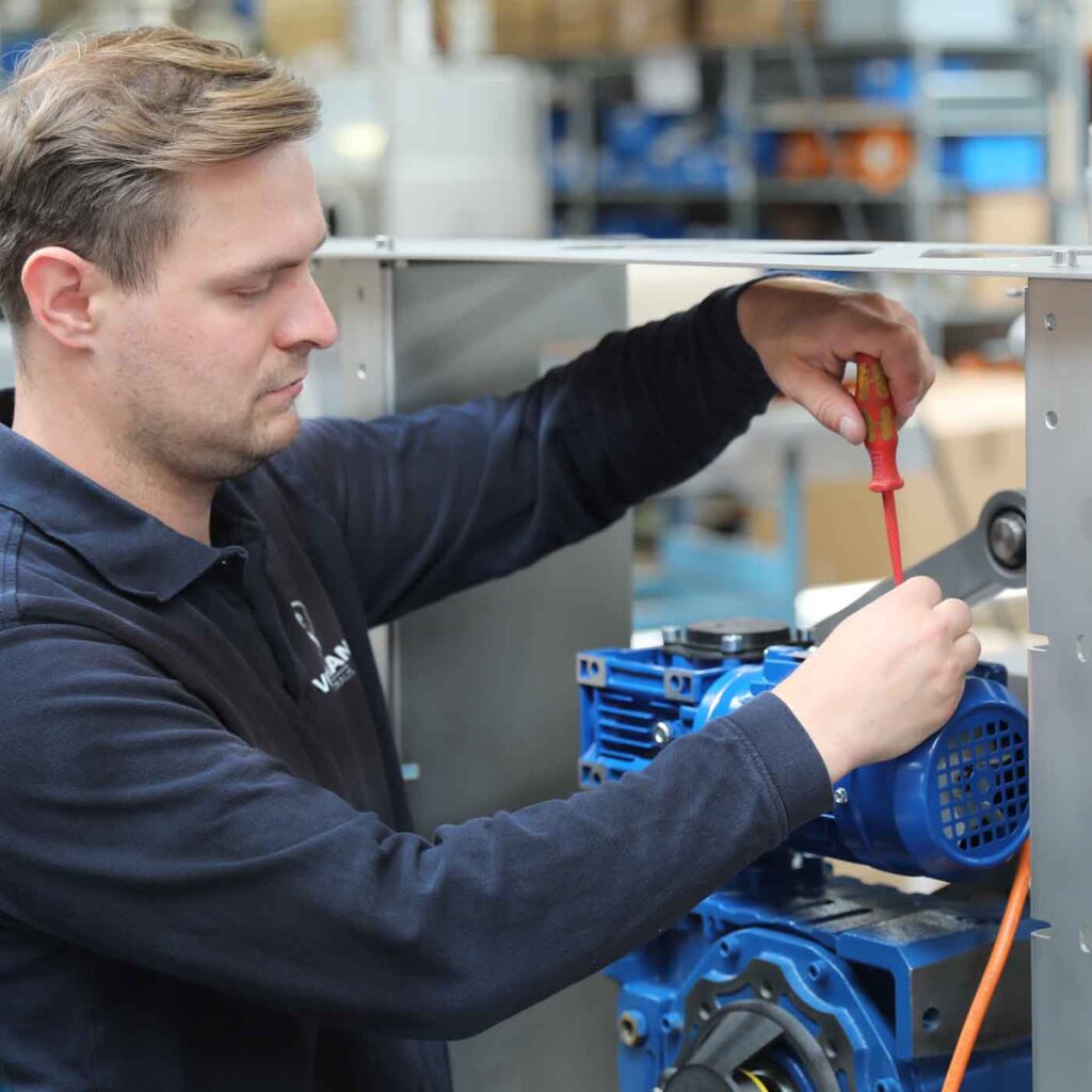 Ein Mitarbiter der Endmontage befestigt einen Motor am Gestell