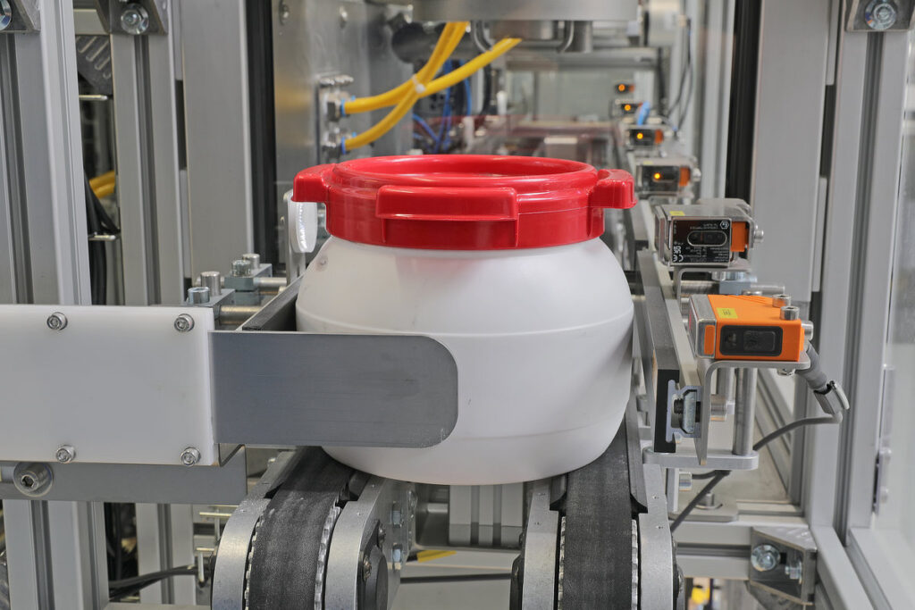 CurTec® wide neck bottle on the conveyor belt of a metal powder filling line.