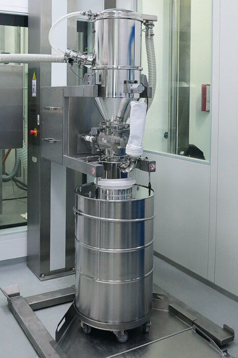 Vakuumförderer Typ PPC an einer Hubsäule, mit einer Zellenradschleuse zur Dosierung. Das Fass inkl. Inhalt wird per Bodenwaage verwogen, und über den Messwert wird die Zellenradschleuse gesteuert.